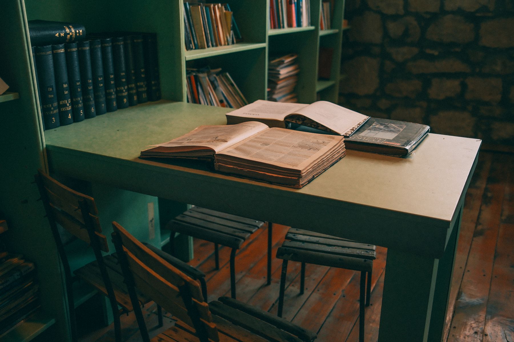 Library with green bookshelves and open books